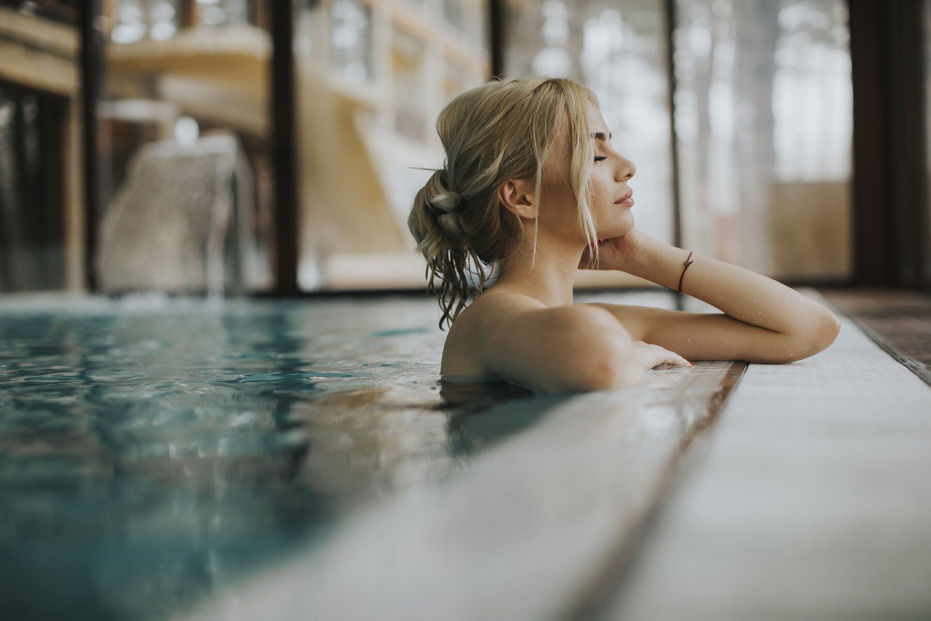 Junge Frau, die sich im Schwimmbad am Beckenrand entspannt