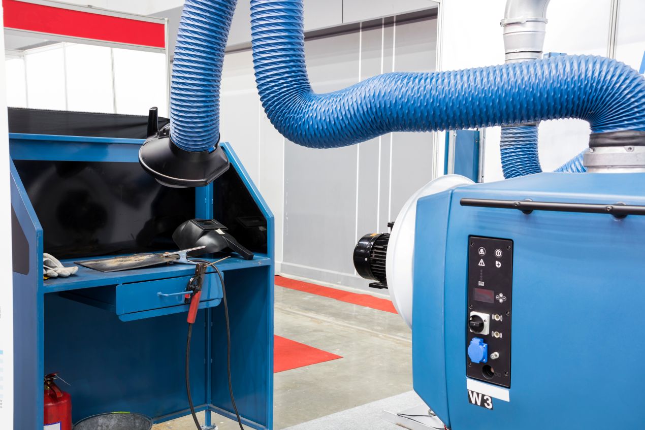 Moderne Schweißkabine mit blauer Absauganlage und flexiblen Absaugarmen zur sicheren Erfassung von Schweißrauch